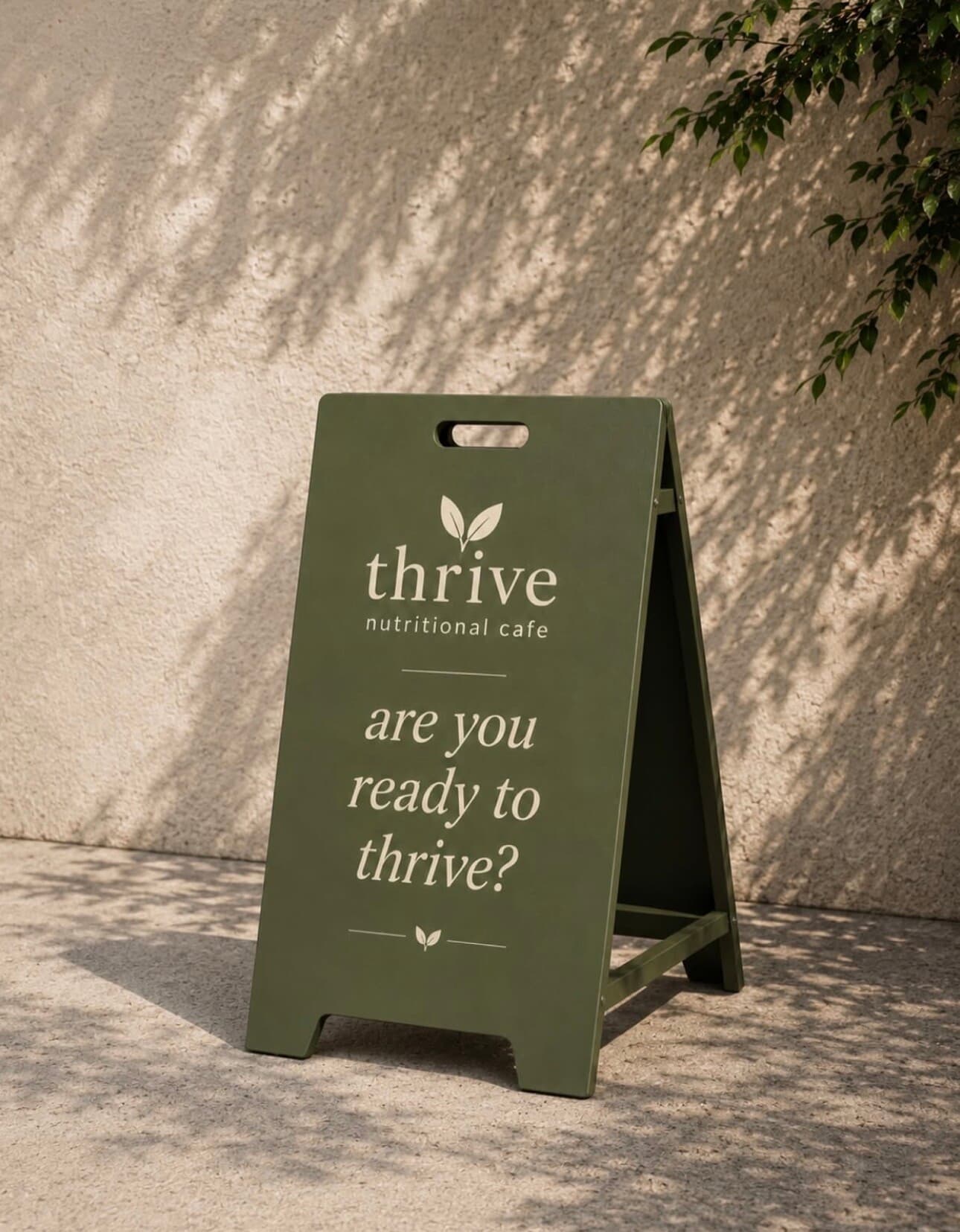 Green Thrive A-board on a sunlit wall with dappled leaf shadows, reading are you ready to thrive